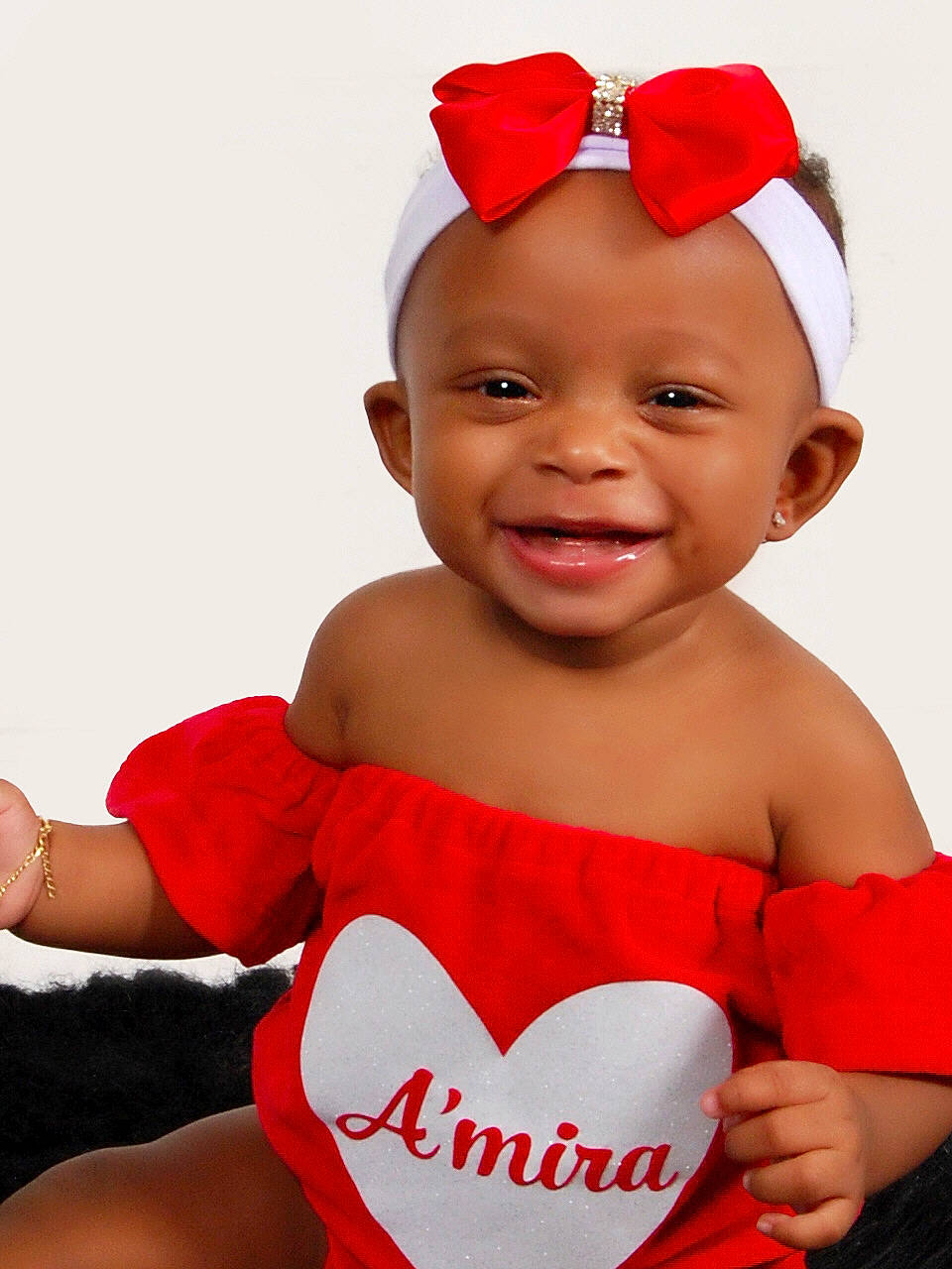 Amira is registered to the contest to win money with this photo: baby, baby_toddler_clothing, cool, eyewear, face, facial_expression, finger, gesture, goggles, happy, headwear, joy, organ, person, pink, product, red, sleeve, smile, standing