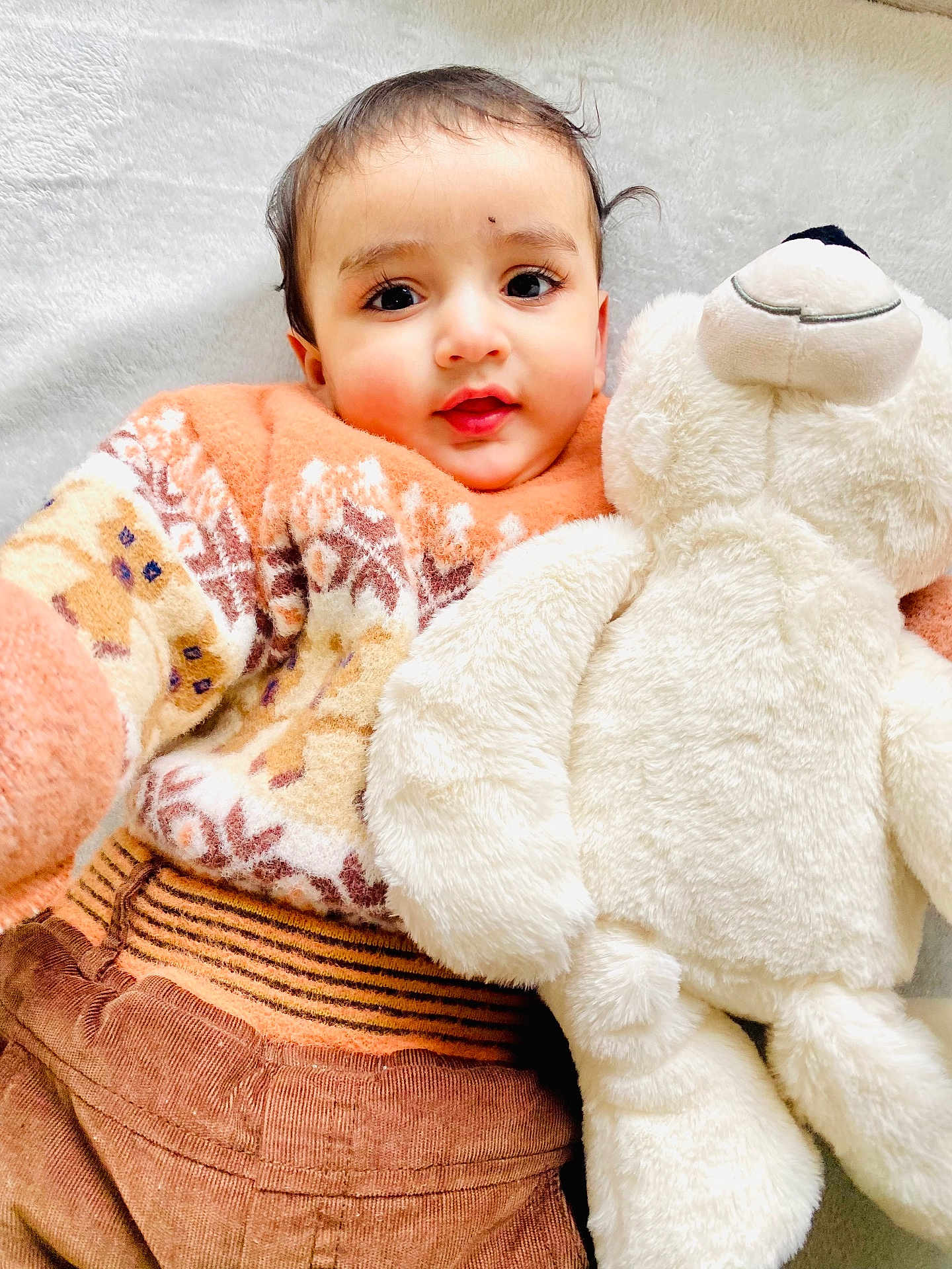 Jujhar joined the competition — help win amazing prizes! baby, child, teddy_bear, plush_toy, sweater, patterned_clothing, brown_pants, soft_texture, cuddly, cute, indoor, portrait, smiling, happy, infant, closeup, cozy, warm_clothing, white_background, person