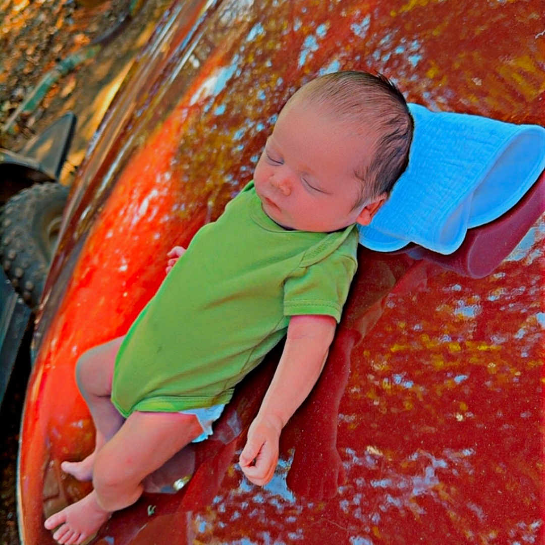 Elliott is registered to the contest to win money with this photo: baby, car, clothing, face, grass, hat, head, machine, outdoorplayarea, outdoors, person, photography, plant, playarea, portrait, spoke, summer, transportation, vehicle, wheel