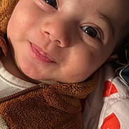 Youssef Adda participe au concours pour gagner de l'argent avec cette photo : baby, close_up, smile, face, eyes, fuzzy_jacket, brown, white_shirt, pillow, red_hearts, infant, cute, skin, child, young, lying_down, cozy, expression, indoors, warm