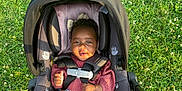 Jordyn joined the competition — help win amazing prizes! baby, car_seat, child, grass, outdoor, sunlight, smile, curly_hair, bow, clothing, safety_harness, infant, nature, greenery, flowers, person, seat, cute, happy, portrait