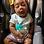 Jordyn is registered to the contest to win money with this photo: baby, car_seat, pacifier, yellow_bow, clothing, infant, cute, yawning, beads, name_beads, purple_shorts, white_shirt, closeup, child, seatbelt, indoors, soft_lighting, adorable, person, portrait