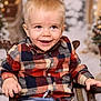 blonde_hair, blue_jeans, casual_clothing, chair, child, cute, face, festive, happy, holiday_background, indoor, person, plaid_shirt, portrait, seated, smiling, toddler, warm_lighting, wooden_chair, young_child