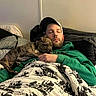 Wrigley is registered to the contest to win money with this photo: animal, bed, blanket, brindle, cap, comfort, cozy, cuddling, cute, dog, face, green_hoodie, human, indoor, man, nap, pet, puppy, rest, sleeping