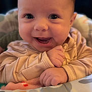Charlotte is registered to the contest to win money with this photo: baby, smiling, close_up, infant, cute, happy, child, face, portrait, young, hands, clothing, pattern, cushion, indoors, warm_light, skin, head, eyes, expression
