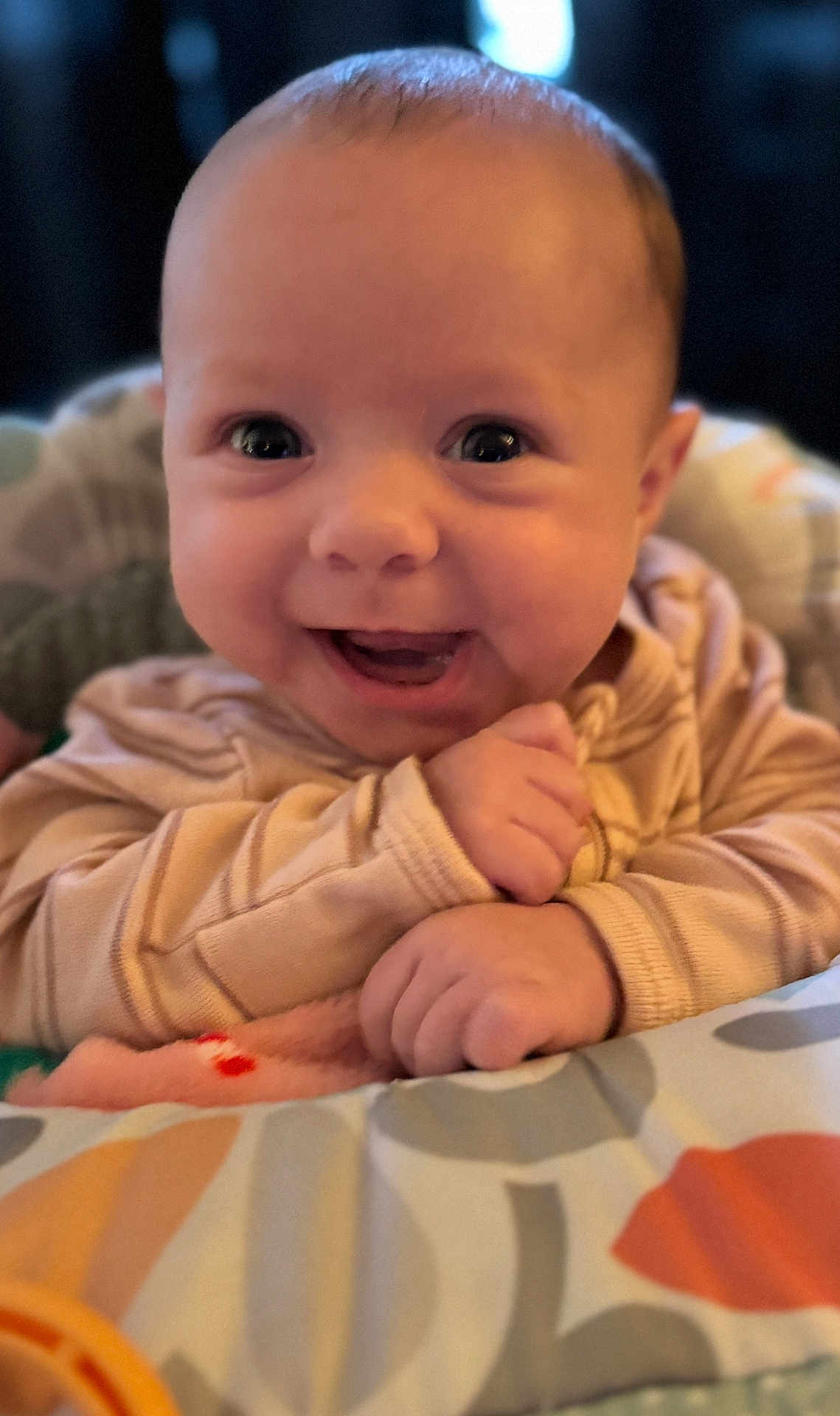 Charlotte is registered to the contest to win money with this photo: baby, smiling, close_up, infant, cute, happy, child, face, portrait, young, hands, clothing, pattern, cushion, indoors, warm_light, skin, head, eyes, expression