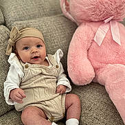 Millie joined the competition — help win amazing prizes! baby, infant, teddy_bear, plush_toy, sofa, couch, headband, clothing, sitting, smile, cute, indoor, person, soft_toy, white_socks, knitwear, child, portrait, furniture, cozy