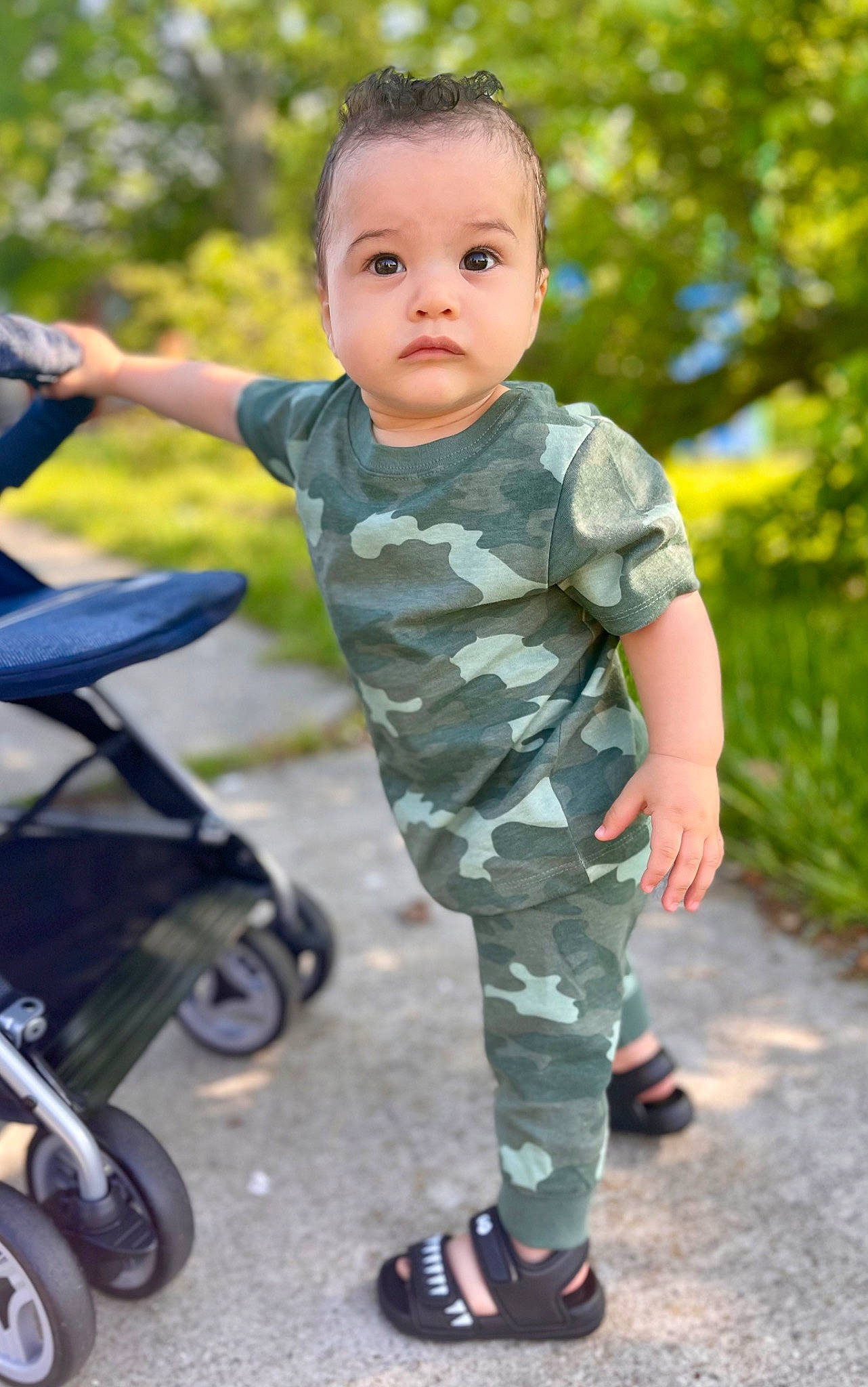 Matthew is registered to the contest to win money with this photo: baby, baby_toddler_clothing, camouflage, child, footwear, grass, happy, leisure, military_camouflage, military_person, military_uniform, people_in_nature, person, personal_protective_equipment, recreation, rolling, sleeve, sneakers, tire, toddler