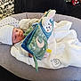Clément participe au concours pour gagner de l'argent avec cette photo : baby, infant, hat, blanket, plush_toy, book, pillow, couch, soft_toy, face, person, indoors, clothing, smile, baby_bed, comfort, relaxation, cute, child, resting