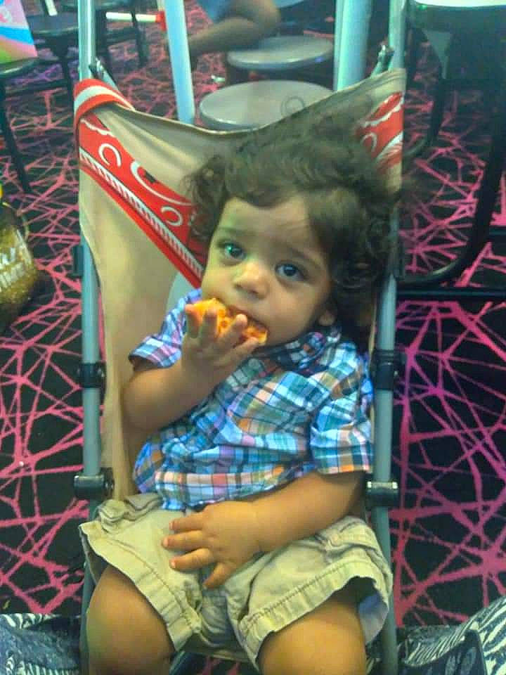 Julian is registered to the contest to win money with this photo: baby, blurred, chair, cheek, child, event, eye, fun, human_leg, lap, leisure, pattern, person, plaid, play, room, shorts, sitting, thigh, toddler