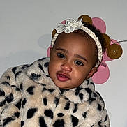 Sia participe au concours pour gagner de l'argent avec cette photo : toddler, child, face, headband, flower, jacket, leopard_print, fur, indoor, portrait, cute, clothing, hand, person, eyebrows, skin, eyes, pink, decoration, wall
