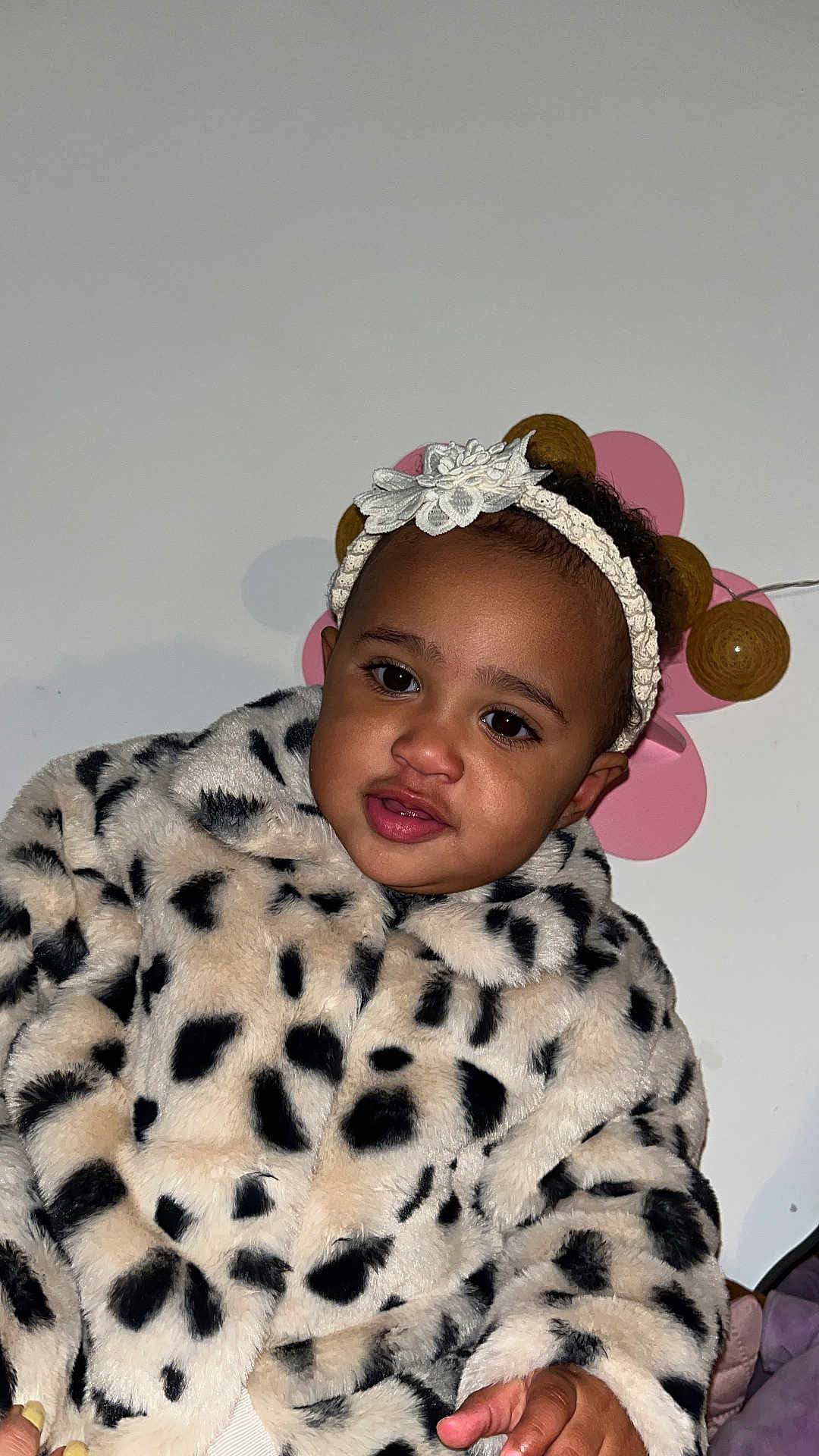 Sia participe au concours pour gagner de l'argent avec cette photo : toddler, child, face, headband, flower, jacket, leopard_print, fur, indoor, portrait, cute, clothing, hand, person, eyebrows, skin, eyes, pink, decoration, wall