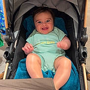 Emilio a rejoint le concours — aidez-le/la à gagner de superbes lots ! baby, stroller, child, smiling, happy, toy, blue_blanket, onesie, indoor, person, infant, seat, baby_toy, cute, legs, head, expression, clothing, closeup, comfort