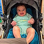 baby, stroller, child, smiling, happy, toy, blue_blanket, onesie, indoor, person, infant, seat, baby_toy, cute, legs, head, expression, clothing, closeup, comfort