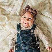 Odayah is registered to the contest to win money with this photo: baby, child, smile, denim_overalls, headband, bow, blanket, cute, infant, happy, portrait, clothing, toddler, person, face, hand, sitting, indoor, white, texture