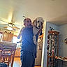 Daisy joined the competition — help win amazing prizes! cabinet, casual_clothing, ceiling_fan, decorations, dog, furniture, happy, holding, home, indoor, kitchen, light, living_room, man, pet, poodle, refrigerator, smile, window, wood_floor