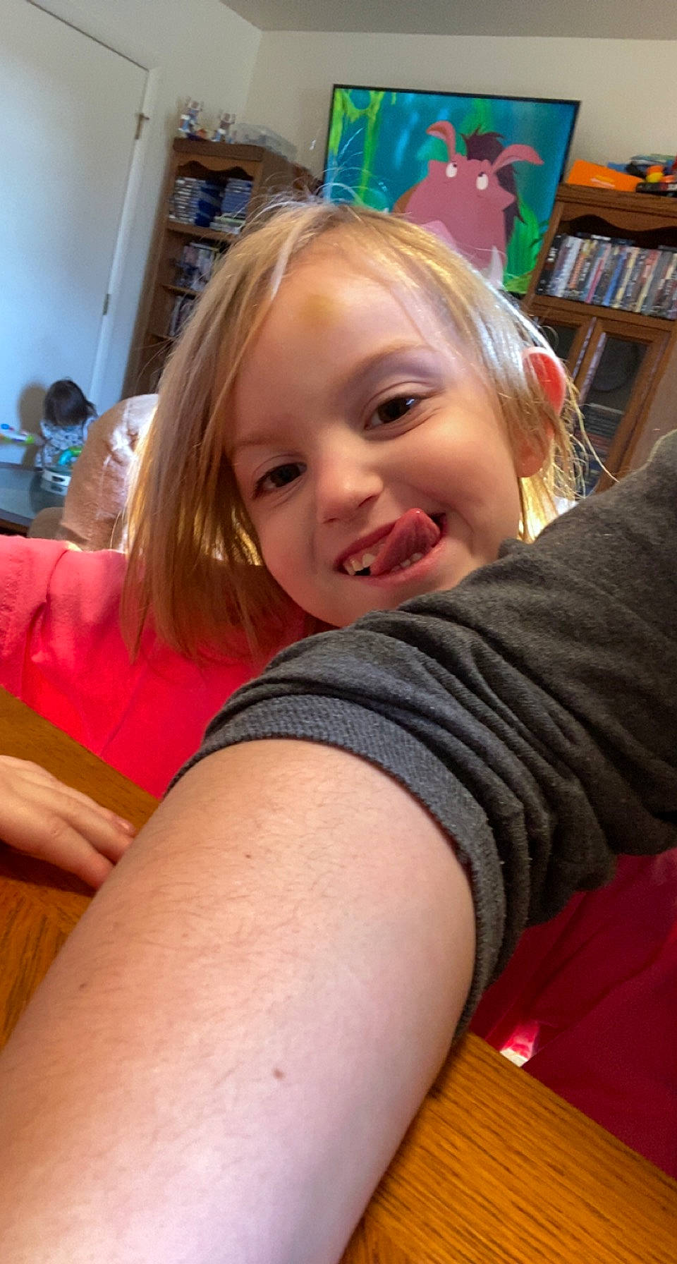 Isabella is registered to the contest to win money with this photo: bookcase, chair, cheek, chin, elbow, finger, gesture, hairstyle, happy, joint, joy, leisure, long_hair, mouth, neck, person, shelf, shoulder, smile, t_shirt