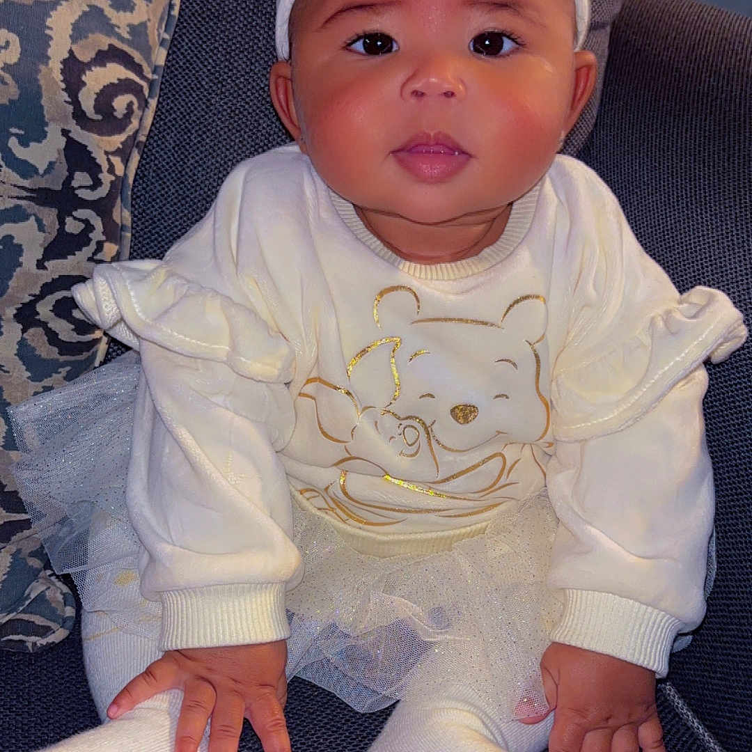 Zhala is registered to the contest to win money with this photo: baby, bodypart, bonnet, cap, clothing, couch, cushion, face, finger, furniture, hand, hat, head, hosiery, pants, person, photography, portrait, sitting, sock