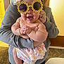 Monroe is registered to the contest to win money with this photo: accessory, adult, baby, child, clothing, cute, face, flower, hand, happy, headband, holding, indoor, pants, person, skin, smile, sunglasses, torso, woman