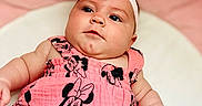 Lydia is registered to the contest to win money with this photo: arm, baby, bow, child, chubby_cheeks, closeup, clothing, cute, expression, hand, headband, indoors, infant, minnie_mouse, person, pink_dress, portrait, skin, soft_background, young_child