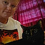 Minnie is registered to the contest to win money with this photo: person, cat, indoor, selfie, curtains, window, red_curtains, smiling, tortoiseshell_cat, pet, face, portrait, casual_clothing, necklace, light, shadow, hair, eyebrow_piercing, holding, cozy