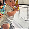 Jt joined the competition — help win amazing prizes! baby, child, standing, playpen, yellow_handle, indoors, curtains, window_blinds, floor, clothing, foot, hand, face, expression, room, light, person, background, curly_hair, sitting