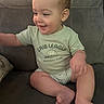 Jt is registered to the contest to win money with this photo: baby, child, smile, tshirt, green_clothing, sitting, couch, furniture, indoor, infant, happy, face, skin, foot, hand, arm, person, cute, young_child, casual