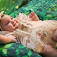 Victoria joined the competition — help win amazing prizes! baby, child, smile, dress, headband, embroidery, lace, green_background, leaf_pattern, infant, cute, happy, portrait, toddler, soft_fabric, reaching_hand, lying_down, closeup, person, indoors