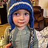 Everett joined the competition — help win amazing prizes! child, toddler, hat, knitted_hat, blue_hat, earflaps, indoor, carpet, recliner, furniture, blanket, curious, portrait, face, person, clothing, long_sleeve, young_child, home, closeup