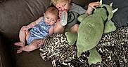 Lyric is registered to the contest to win money with this photo: baby, blanket, blond_hair, bottle, brown_couch, carpet, child, clothing, couch, curly_hair, cute, drink, family, indoor, leather, leopard_print, plush_toy, relaxing, sitting, toddler