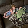 Lyric is registered to the contest to win money with this photo: child, baby, toddler, couch, leather, blanket, plush_toy, bottle, drink, sitting, indoor, carpet, clothing, curly_hair, blond_hair, brown_couch, leopard_print, relaxing, cute, family