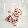 Lyric is registered to the contest to win money with this photo: baby, infant, cute, smiling, tongue_out, headband, pink_overalls, white_top, ribbons, playful, portrait, child, happy, indoors, studio, photography, person, face, crawling, adorable