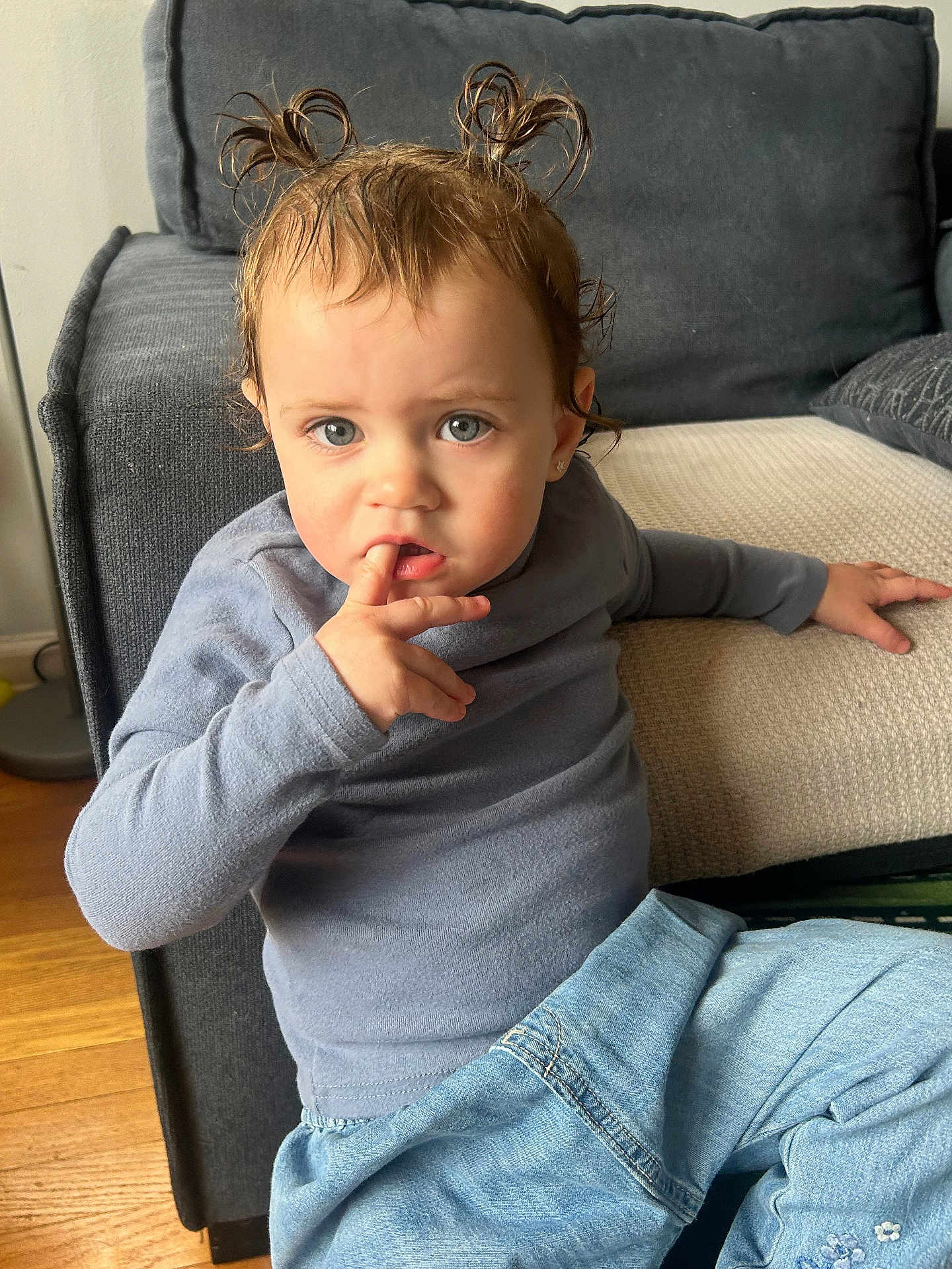 Phoenix joined the competition — help win amazing prizes! child, toddler, baby, pigtails, curious_expression, finger_in_mouth, blue_shirt, jeans, earring, couch, living_room, indoor, portrait, sitting, hardwood_floor, messy_hair, candid, furniture, closeup, eyes
