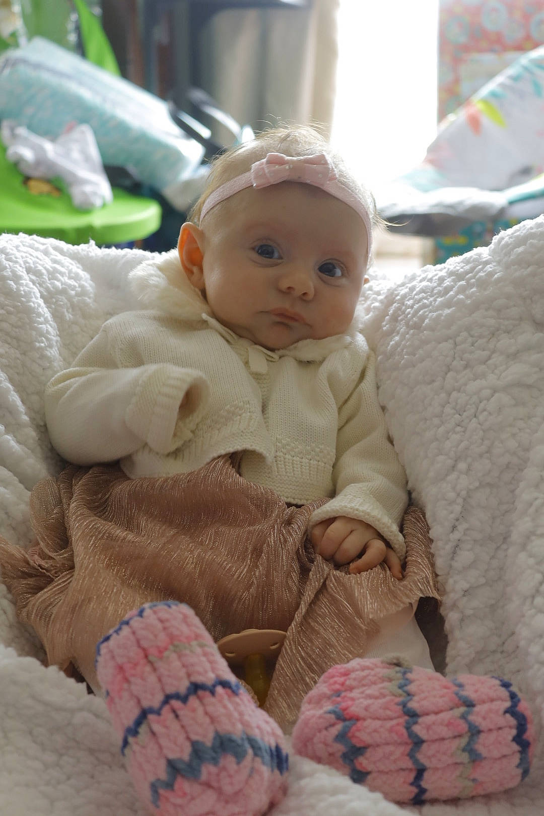 Mya is registered to the contest to win money with this photo: baby, baby_products, baby_toddler_clothing, cheek, child, comfort, eye, fur, headgear, iris, knit_cap, linens, pattern, person, pink, sitting, skin, textile, toddler, wool