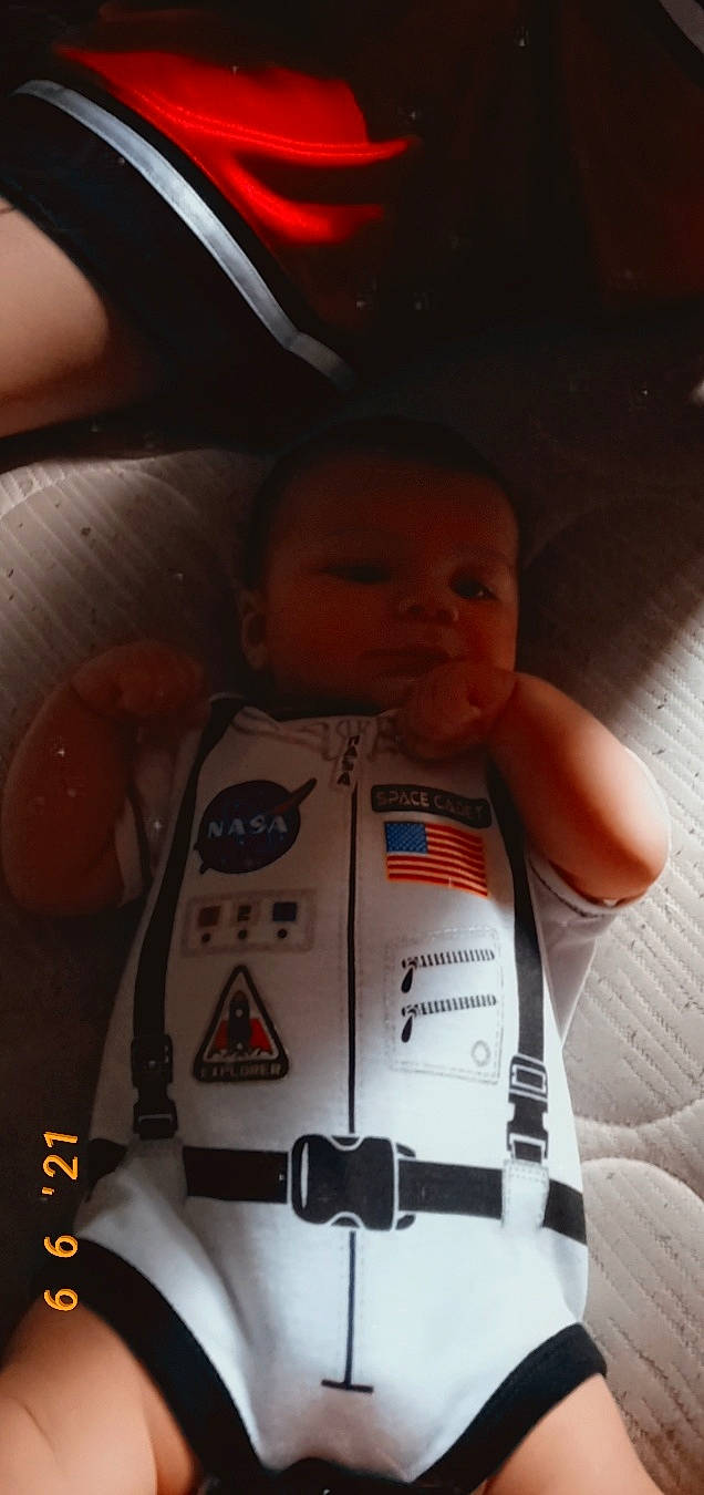 Johnathan is registered to the contest to win money with this photo: automotive_lighting, baby, baby_products, carmine, child, chin, eye, face, finger, fun, head, mouth, nose, orange, person, personal_protective_equipment, skin, space, t_shirt, toddler