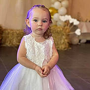 Kamèlya a rejoint le concours — aidez-le/la à gagner de superbes lots ! child, girl, white_dress, portrait, indoor, balloons, decoration, curious_expression, hands_clasped, young_child, event, celebration, floor_tiles, soft_lighting, face, ears, blue_eyes, short_hair, tulle_skirt, bow