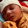 Kobe is registered to the contest to win money with this photo: baby, sleeping, infant, cap, orange_clothing, closeup, face, peaceful, resting, soft_light, person, newborn, skin, cute, headwear, cozy, portrait, human, arm, indoor
