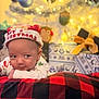 Myles joined the competition — help win amazing prizes! baby, christmas_hat, blanket, holiday, festive, smile, face, infant, indoors, decorations, christmas_tree, lights, gift, present, red, black, plaid, cute, cozy, celebration