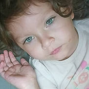 Emberlee is registered to the contest to win money with this photo: child, toddler, curly_hair, blue_eyes, face, hand, blanket, shirt, indoor, portrait, cute, young, person, resting, cozy, expression, casual, soft_lighting, closeup, skin