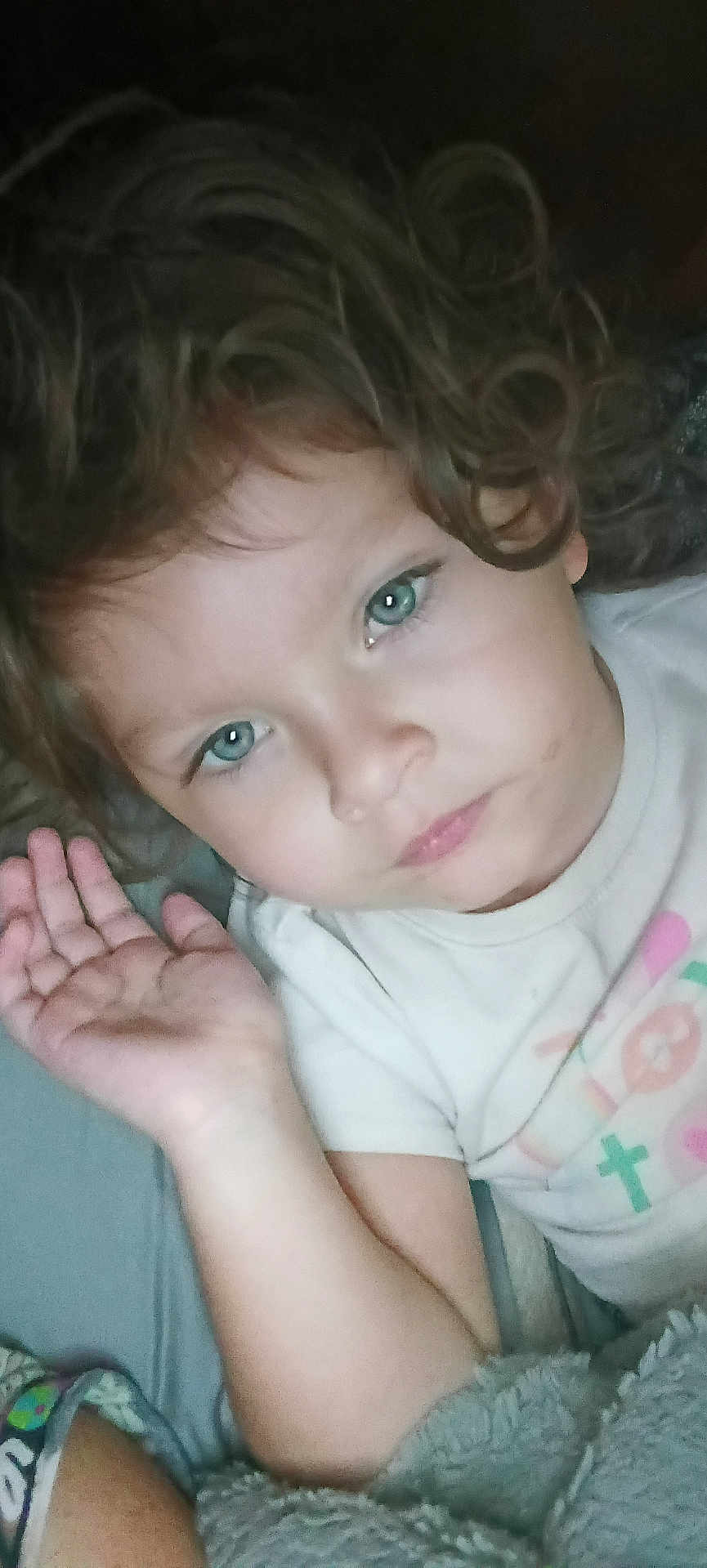 Emberlee is registered to the contest to win money with this photo: child, toddler, curly_hair, blue_eyes, face, hand, blanket, shirt, indoor, portrait, cute, young, person, resting, cozy, expression, casual, soft_lighting, closeup, skin