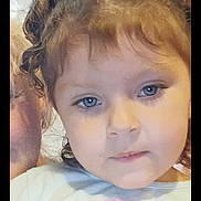 Emberlee joined the competition — help win amazing prizes! child, girl, face, blue_eyes, curly_hair, hair_buns, portrait, indoor, curtain, person, clothing, cartoon_character, tshirt, expressionless, closeup, human, young_child, cute, casual, background