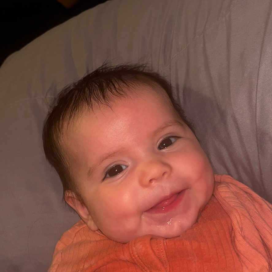 Evelyn is registered to the contest to win money with this photo: baby, bodypart, clothing, couch, cushion, face, finger, furniture, hand, happy, head, homedecor, knitwear, mouth, newborn, person, photography, portrait, smile, sweater