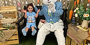 Emma Renae joined the competition — help win amazing prizes! child, bunny_costume, person, bench, paper_chains, decorations, carrots, flowers, grass, indoor, smiling, blue_clothing, toy, holiday_theme, celebration, happy, costume, seated, playful, event