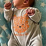 baby, infant, blanket, blue, stars, onesie, orange, bear, pattern, sleepwear, fist, lying_down, cute, newborn, soft, warm, clothing, person, portrait, indoor