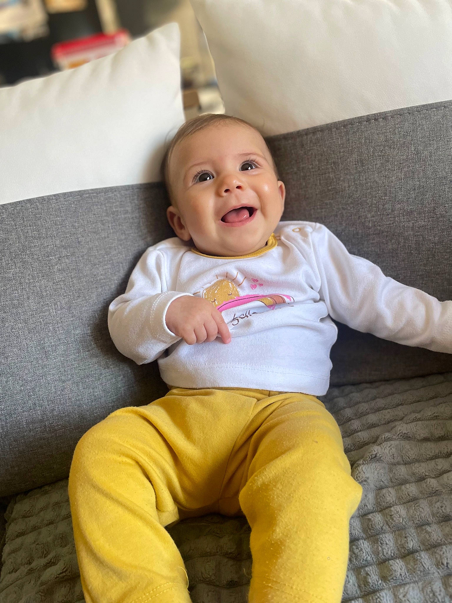 Thalya participe au concours pour gagner de l'argent avec cette photo : baby, baby_toddler_clothing, cheek, child, comfort, couch, eye, face, happy, head, human_body, human_leg, knee, leg, person, sleeve, smile, sportswear, t_shirt, thigh