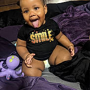 Autumn is registered to the contest to win money with this photo: baby, bodypart, clothing, couch, face, finger, furniture, hand, happy, head, mouth, person, photography, portrait, purple, shorts, sitting, smile, sphere, t_shirt