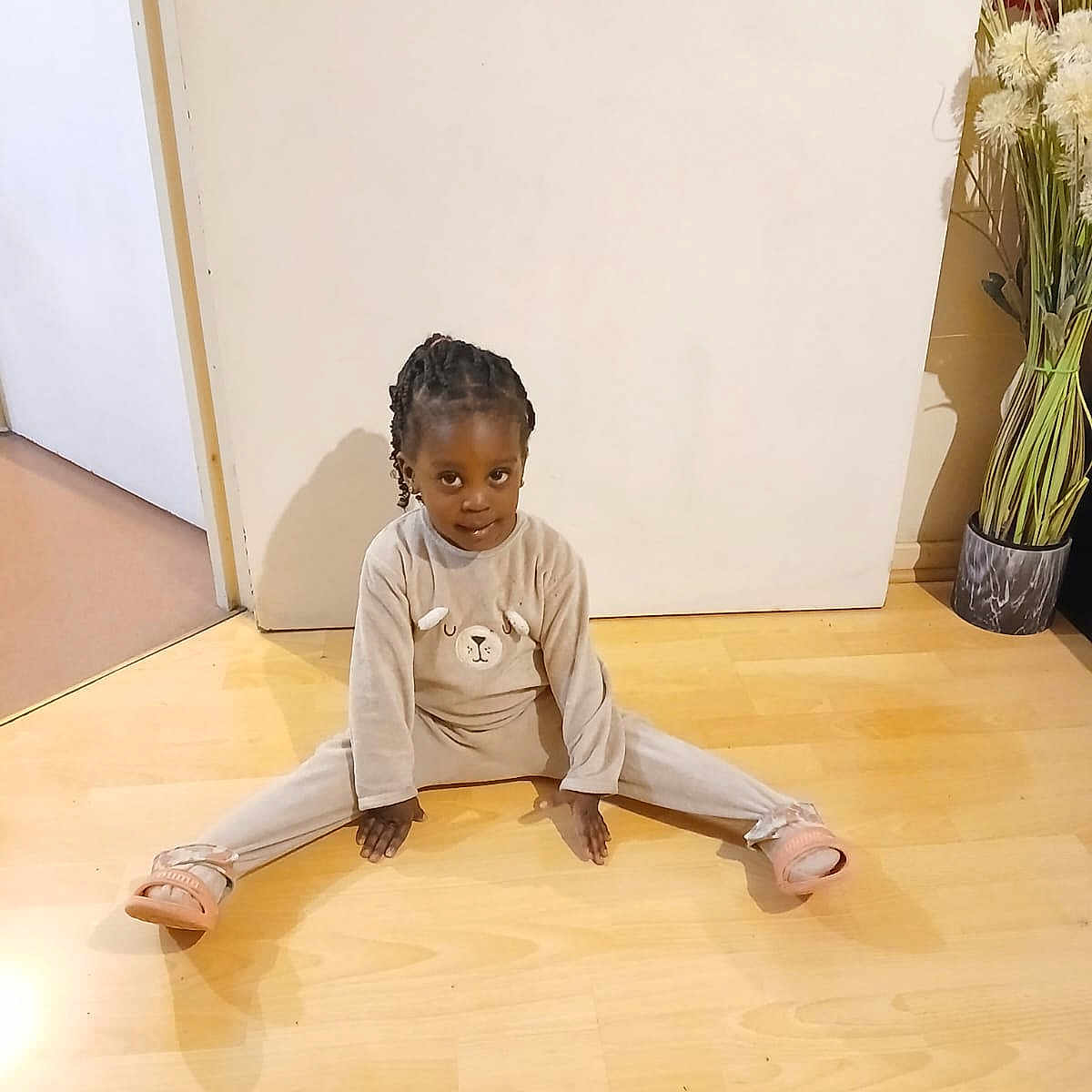 Malaïka-Yireh a rejoint le concours — aidez-le/la à gagner de superbes lots ! animal_face, braided_hair, child, cozy, curious, cute, door, expression, floor, home, indoor, legs_spread, long_sleeves, pajamas, plant, pot, sitting, slippers, wooden_floor, young_child