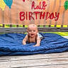 Stetson joined the competition — help win amazing prizes! baby, child, smiling, blanket, wooden_deck, banner, balloons, outdoor, celebration, half_birthday, happy, infant, person, cute, sunlight, blue, red_text, green_balloon, yellow_balloon, portrait