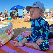 Mark is registered to the contest to win money with this photo: toddler, child, beach, sand, swimsuit, cap, umbrella, people, sunny, outdoor, play, colorful, mat, pool, baby_bottle, summer, vacation, foot, portrait, relaxation