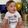 Mark is registered to the contest to win money with this photo: baby, child, blue_eyes, onesie, birthday, balloon, happy, smiling, diaper, sitting, hand, plant, indoor, celebration, face, person, clothing, table, decorations, home